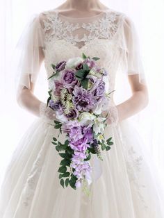 a woman in a wedding dress holding a purple and white bouquet