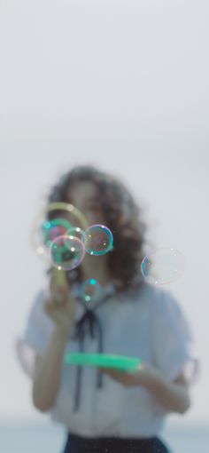 a woman blowing bubbles in front of her face and holding a green frisbee