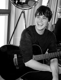 a young man sitting in front of a guitar