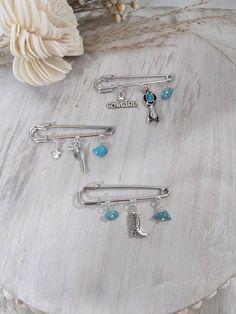 three different types of hair pins on a wooden table next to flowers and seashells