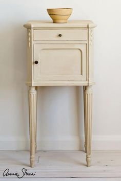 an old white cabinet with a bowl on top