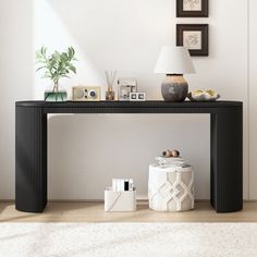 a black console table sitting on top of a wooden floor next to a white rug