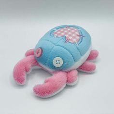 a pink and blue stuffed animal laying on top of a white table