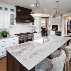 a kitchen with marble counter tops and an island in front of the stove top oven