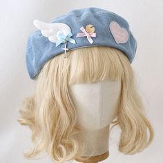 a blonde wig wearing a blue hat with angel wings on it's side and a cross at the top