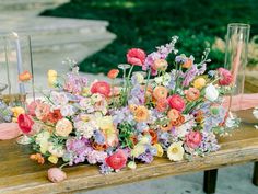 an arrangement of flowers and candles on a wooden table with glass vases in the background