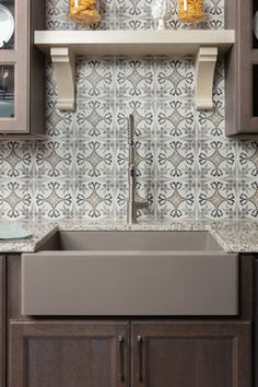 a kitchen sink with brown cabinets and tile backsplash