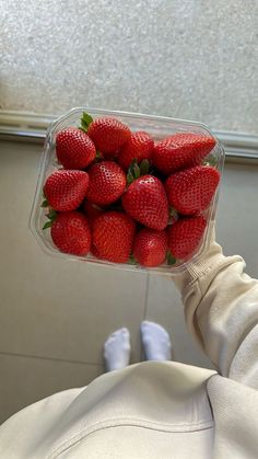 a person holding a plastic container full of strawberries