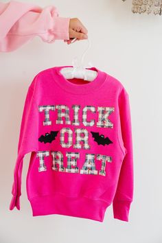 Get ready for the spookiest night of the year with our MINI KIDS GINGHAM TRICK OR TREAT PULLOVER! This hot pink pullover features bold blue gingham letters spelling out "Trick or Treat" and playful black bat patches. Perfect for your little one's Halloween adventures. All orders are currently shipping within 14 business days. To receive item quicker, expedited shipping is available at checkout. **ALL HALLOWEEN ORDERS MUST BE PLACED WITH EXPEDITED SHIPPING TO GUARANTEE DELIVERY BY OCT. 31 IF PLAC Playful Letter Print Sweatshirt For Fall, Playful Pink Sweatshirt With Letter Print, Halloween Adventure, Pink Pullover, Black Bat, First Halloween, Oct 31, Blue Gingham, Halloween Outfits