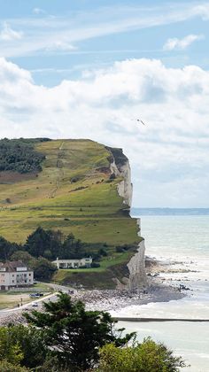 a view of the beach and cliffs from across the water with people walking on it