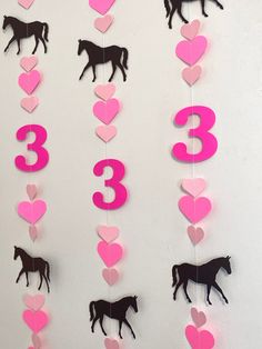 pink and black horse themed birthday decoration with heart shaped paper cutouts on white wall