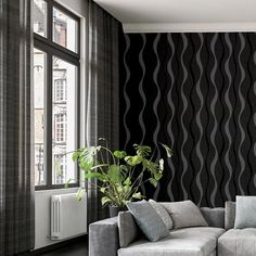 a living room with black and white wallpaper, grey couches and large windows