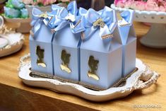 three little blue boxes with bows on them are sitting on a table next to flowers