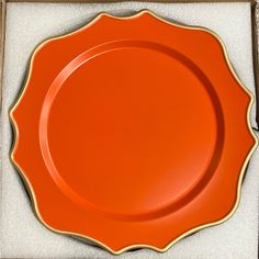 an orange plate with gold trim in a box