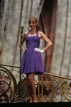 a woman in a purple dress standing on stage