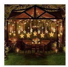 an outdoor gazebo with stars hanging from it's sides and lights on the ceiling