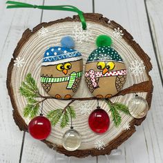 two owls sitting on top of a piece of wood with ornaments hanging from the tree