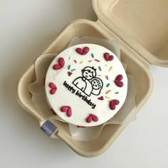 there is a cake in the box with hearts on it and a sticker that says happy birthday