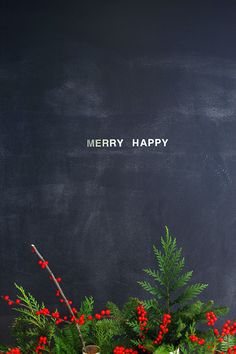 a blackboard with the words merry happy written on it and some plants in front