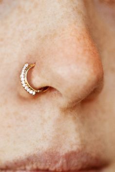 a woman's nose with a gold nose ring on top of her nose and the bottom half of her nose