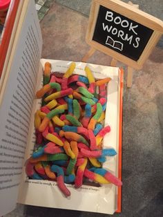 a pile of colorful candy worms sitting on top of a book next to a sign