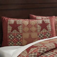 a bed with red and brown stars on the pillow cases next to a night stand