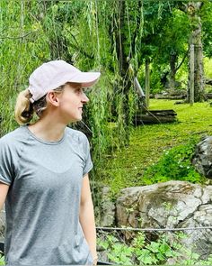 a woman standing next to a giraffe on a lush green forest covered field