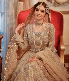 a woman sitting in a chair wearing a wedding dress and tiara with pearls on it