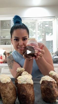 a woman is holding up some baked potatoes