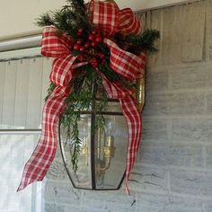 a lantern hanging from the side of a building with a red and white bow on it