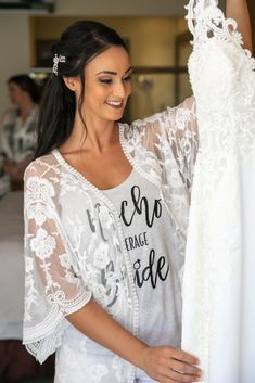 a woman is smiling while looking at her wedding dress hanging on a rack in the room