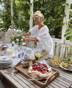 a woman in white dress sitting at a table with food