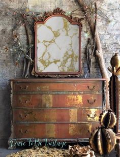 an old dresser with a mirror on top and other items around it in front of a brick wall