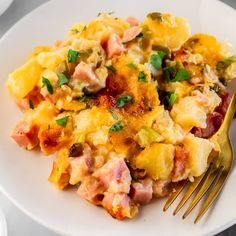 an omelet with ham, cheese and parsley on a white plate next to a fork