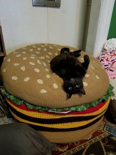 a black cat laying on top of a giant hamburger