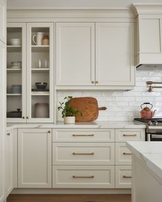 a kitchen with white cabinets and wooden cutting board on the counter top next to an oven