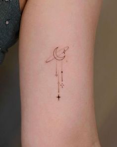 a small tattoo on the back of a woman's left arm with a crescent and stars