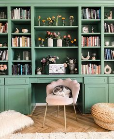 a green bookcase filled with lots of books next to a chair and vases