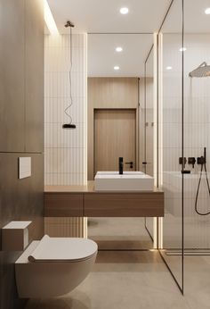 a modern bathroom with a toilet, sink and shower in the corner is lit by recessed lighting