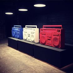 three boomboxes are on display in a dark room