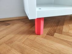 a red and white shelf sitting on top of a hard wood floor