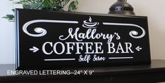 a coffee bar sign sitting on top of a black shelf next to a potted plant