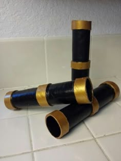 three black and gold pipes sitting on top of a white tile floor