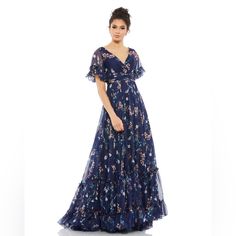 Whimsical Floral Maxi Dress With A Ruched Bodice And Faux-Wrap V-Neckline, Sheer Flutter Sleeves, Pleated Waistband, And A Tiered Flowy Skirt. Back Zipper Imported Short Sleeve Maxi Length Size & Fit Approx. Length From Shoulder To Hem: 62.5" Material & Care Ieena For Mac Duggal Dress - Fully Lined, 100% Polyester 100% Polyester Spot Clean New Without / Never Worn Still Has Security Tag On D/9 Mac Duggal Dress, Mac Duggal Dresses, Maxi Dress Navy, Ruched Bodice, Mac Duggal, Flounce Sleeve, Flowy Skirt, Flutter Sleeves, Floral Maxi