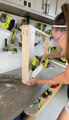 a woman working on a piece of wood in a garage with tools and pegs