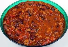 a green bowl filled with chili and beans