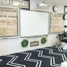 a classroom with black and white carpet, bulletin boards on the wall and potted plants