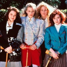 four women standing next to each other in front of trees