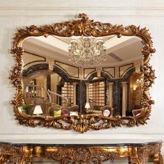 an ornate mirror hangs on the wall next to a console table with a chandelier