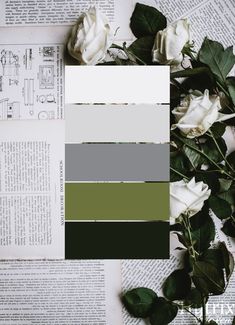 white roses and green leaves on top of an open book with the same color scheme